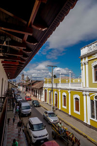 Cars on street by buildings against sky in city