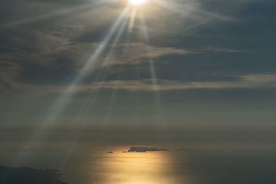 Sunlight streaming through clouds over sea