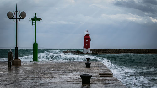 Lighthouse by sea against sky