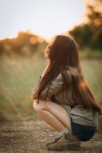 Side view of young woman crouching on field