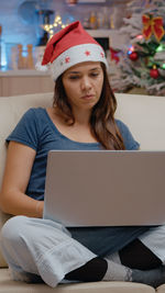 Young woman using laptop while sitting on sofa at home