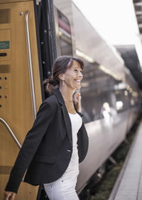 Happy businesswoman disembarking train