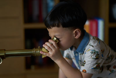 Boy looking through telescope at home