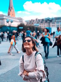 Smiling mid adult backpack woman standing on street in city