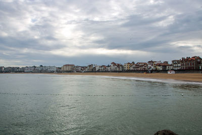 Scenic view of sea by buildings against sky