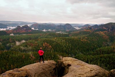 Rear view of person standing on mountain against sky