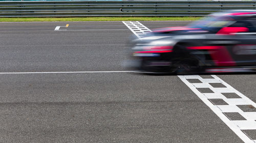 Race car blurred motion crossing the finish line on international circuit speed track, motion blur.