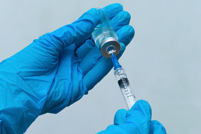 Cropped hands of doctor holding syringe with vial at hospital