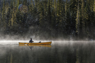 Man in boat on lake against trees