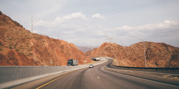 Road leading towards rocky mountains against sky