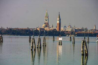 View of wooden posts in lake against sky