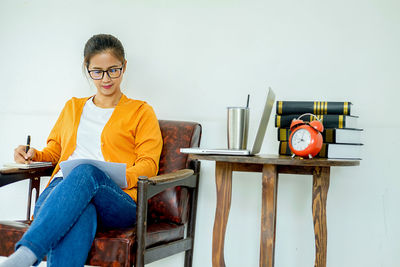 Portrait of young woman using phone while sitting on table