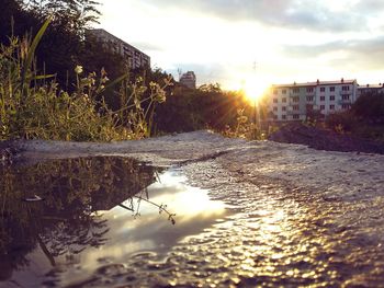 Scenic view of river in city against sky at sunset