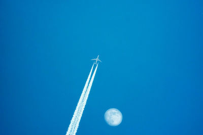 Low angle view of airplane flying against blue sky