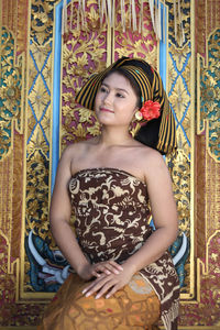 Portrait of young woman standing against wall