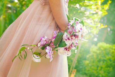 Midsection of woman holding pink flower