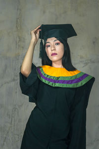 Portrait of young woman standing against wall