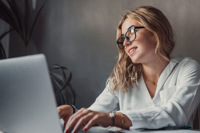 Portrait of young woman using laptop at table