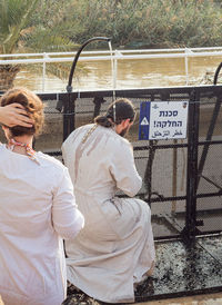 Rear view of men standing by fence