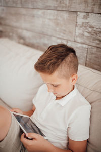 High angle view of boy looking away while sitting on sofa