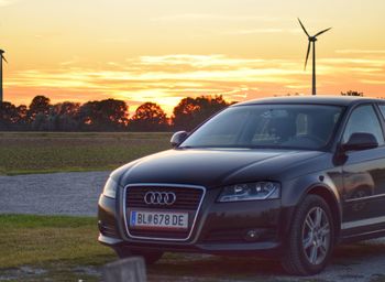 Car on field against sky at sunset