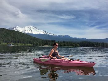 Woman kayaking in lake against cloudy sky
