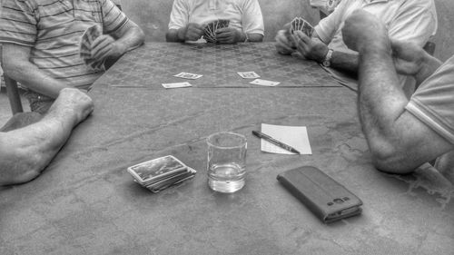 Mid section of men playing cards on table