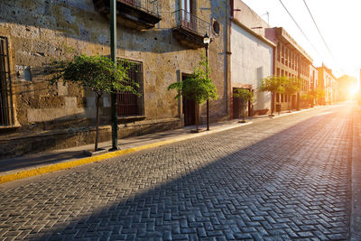 Empty road by buildings in city