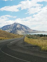 Road by mountains against sky