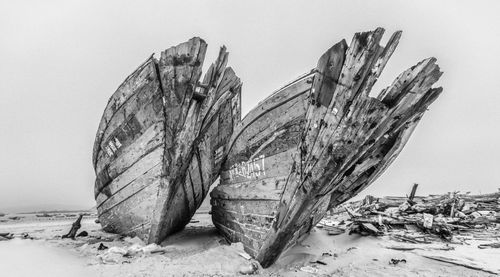 Low angle view of abandoned boats on beach against clear sky