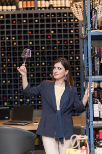 Portrait of young woman standing in  wine shop , holding wine glass 