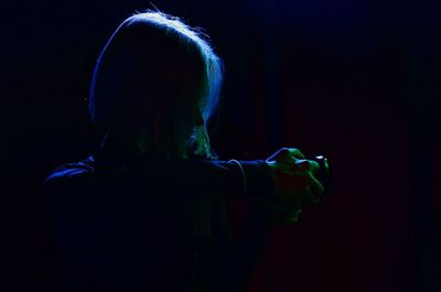 Rear view of woman wearing mask against black background