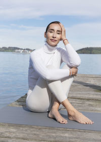 Beautiful woman with head in hand sitting on jetty