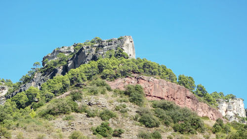 Low angle view of stone wall against clear blue sky