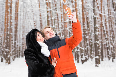 Young woman photographing with mobile phone during winter