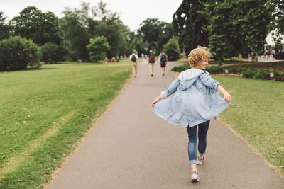 Rear view of young woman walking on walkway at park