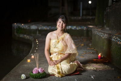 Portrait of young woman standing against illuminated city at night