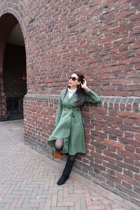 Woman standing against brick wall in city