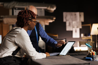 Side view of woman using laptop at office