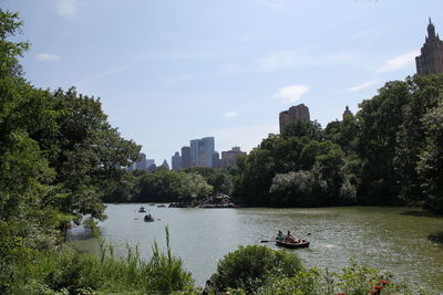 Boats in river by city against sky