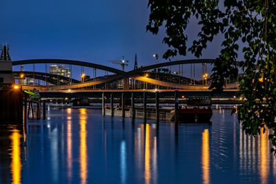 Illuminated bridge over river against sky at night