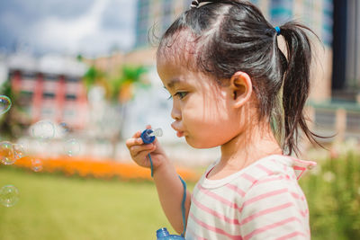 Girl blowing bubbles at park