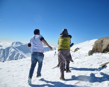 Rear view of people standing on snow covered mountain