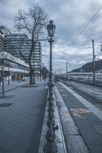 Street by railroad tracks in city against sky