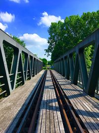 Footbridge over railroad tracks against sky