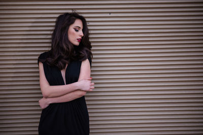 Beautiful young woman standing against shutter