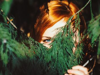 Close-up portrait of young woman by branches
