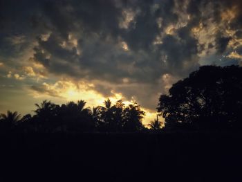 Silhouette trees on landscape against sky at sunset