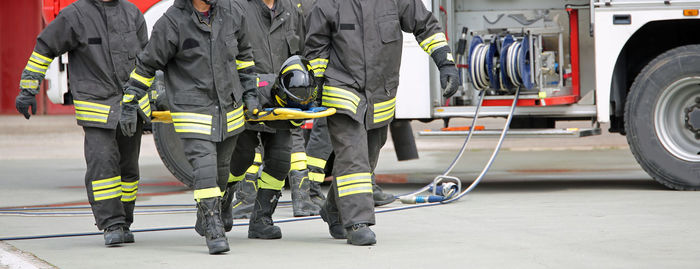 Low section of firefighters walking on road