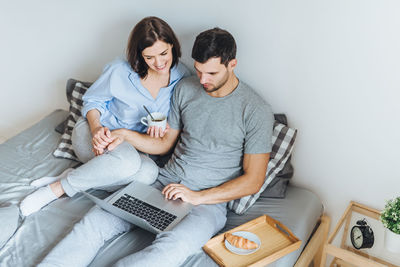 High angle view of couple watching video over laptop on bed at home